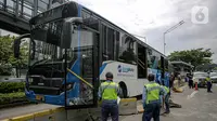 Petugas memeriksa kondisi bus Transjakarta yang menabrak separator busway di kawasan Bundaran Senayan, Jakarta, Jumat (3/12/2021). Kecelakaan mengakibatkan bagian depan bus Transjakarta rusak karena menghantam separator busway. (Liputan6.com/Faizal Fanani)