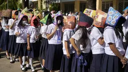 Siswa mengenakan pelindung di kepala mereka untuk perlindungan selama latihan gempa di sebuah sekolah dasar di Metro Manila, Filipina, Kamis (8/9/2022). Filipina melakukan latihan gempa nasional kuartal ketiga sebagai bagian dari upaya untuk membuat publik mengetahui protokol dan tanggapan selama bencana. (AP Photo/Aaron Favila)