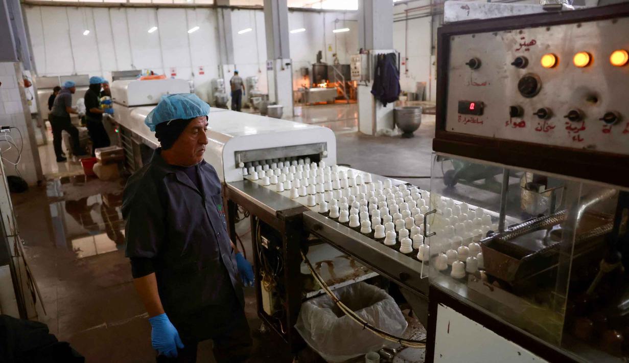 Pabrik ini juga menghadapi keterbatasan operasional karena kekurangan bahan bakar dan listrik serta tenaga kerja secara drastis. Tampak dalam foto, seorang karyawan Palestina memeriksa kue manis khas lokal yang dikenal sebagai "al-Shatwi" (kue musim dingin) Crimbo, saat pabrik Al-Arees secara bertahap melanjutkan produksinya setelah terhenti akibat perang, di Deir al-Balah, Jalur Gaza tengah pada 12 Januari 2026, (Bashar Taleb/AFP)