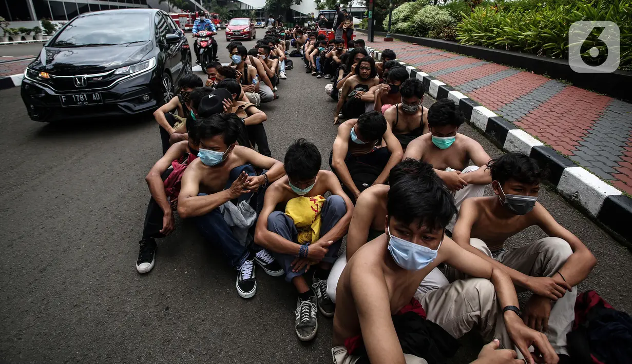 Sejumlah pemuda diamankan di Lapangan Futsal Gedung DPR, Kompleks, Parlemen, Senayan, Jakarta, Kamis (8/10/2020). Ratusan pemuda yang diamankan oleh petugas ini diduga hendak ikut demonstrasi menolak pengesahan Rancangan Undang-Undang Cipta Kerja menjadi UU di gedung DPR. (Liputan6.com/Johan Tallo)