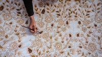 Seorang pekerja mewarnai kain batik saat proses pembuatan di Sidoarjo, Jawa Timur, Sabtu (1/10/2022). Indonesia akan memperingati Hari Batik Nasional pada 2 Oktober. (JUNI KRISWANTO/AFP)