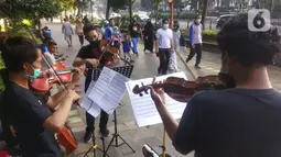 Musisi lokal Bogor memainkan musik klasik di pedestrian Kebun Raya, Jalan Pajajaran, Bogor, Jawa Barat, Minggu (14/6/2020). Untuk memenuhi kebutuhan hidup akibat sepinya job pertunjukan selama pandemi COVID-19, mereka memilih mengamen saat warga berolahraga. (merdeka.com/Arie Basuki)