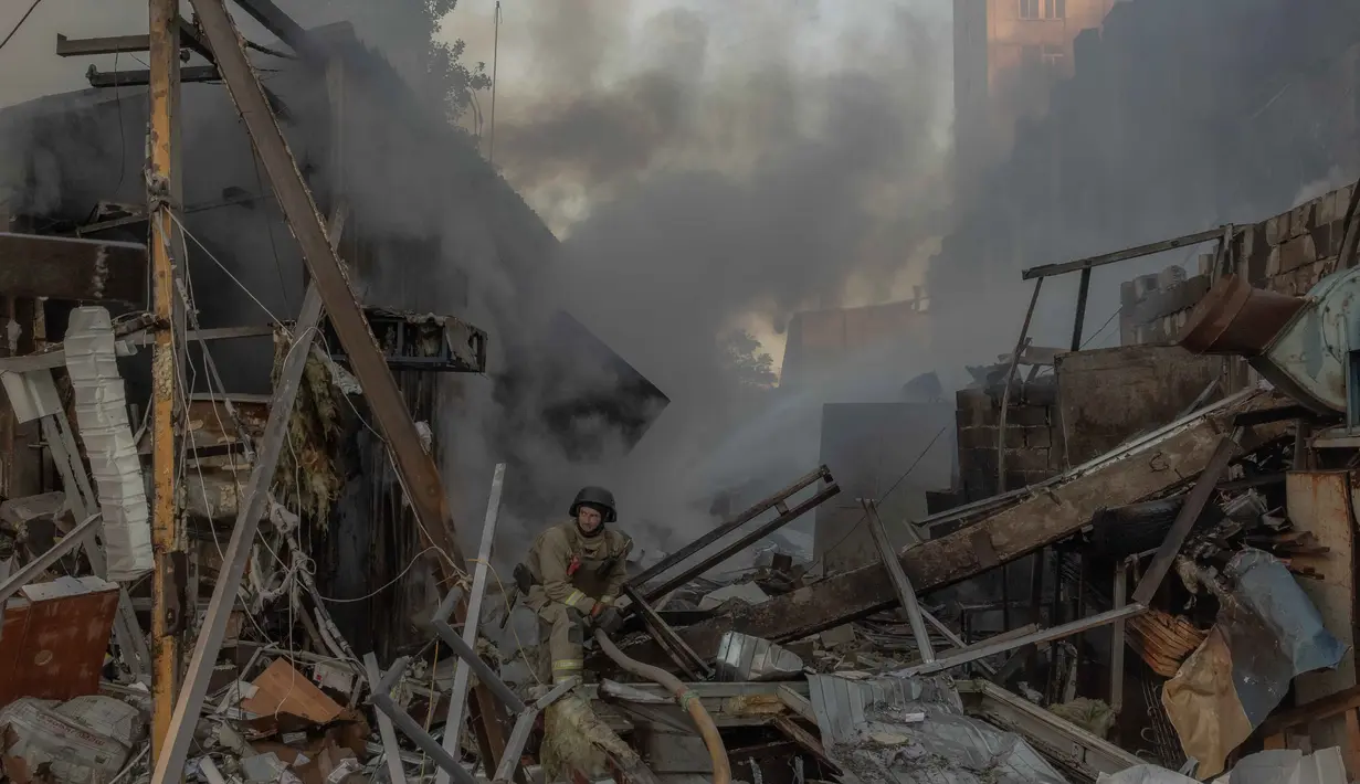 Seorang petugas pemadam kebakaran bekerja di lokasi di samping gedung apartemen bertingkat yang rusak akibat serangan rudal dan pesawat tak berawak besar-besaran Rusia di Kyiv pada Selasa 2 Juni 2026, di tengah invasi Rusia ke Ukraina. (Roman PILIPEY/AFP)