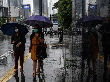 Pejalan kaki menggunakan payung saat hujan di kawasan Jakarta, Selasa (16/2/2021). Setelah memulai vaksinasi COVID-19 tahap pertama dengan sasaran petugas kesehatan, kini pemerintah menargetkan lansia dan petugas pelayanan publik untuk penerima vaksinasi tahap kedua. (Liputan6.com/Johan Tallo)