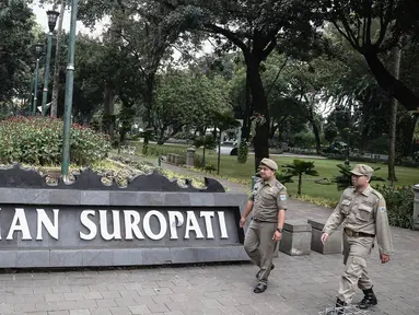 Dua petugas Satpol PP melakukan patroli di kawasan Taman Suropati, Jakarta, Selasa (14/6). Kini, Taman Suropati disterilkan dari PKL dan bersih dari parkir liar yang biasa terlihat di bahu jalan tepian taman. (Liputan6.com/Faizal Fanani)