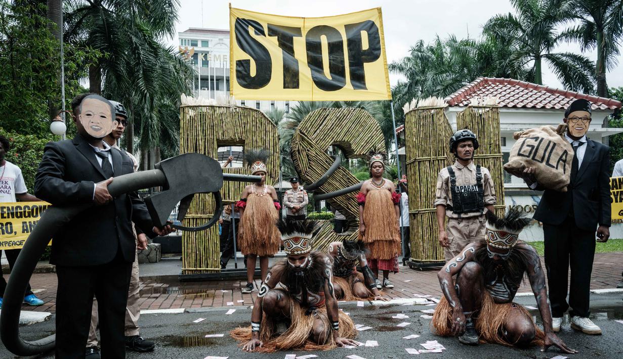 Mereka menilai proyek ini sebagai solusi palsu yang mengancam hutan alam dan ruang hidup masyarakat adat demi ambisi bioetanol. Tampak dalam foto, aktivis Greenpeace Indonesia bersama beberapa pemuda Papua menggelar aksi teatrikal saat berunjuk rasa di depan Kantor Kementerian Koordinator bidang Perekonomian, Jakarta, Kamis (18/12/2025). (Yasuyoshi Chiba/AFP)