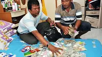Anggota Resmob Polda Kalbar mengemas barang bukti uang taruhan di rumah tersangka bandar judi togel, saat penggebrekan di Komplek Perumahan Cempaka Putih, Jalan Adisucipto, Kubu Raya, Kalbar. (ANTARA)