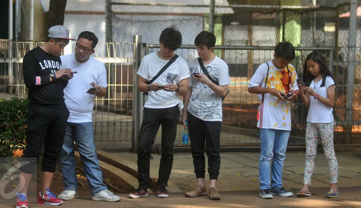Sejumlah pemuda dan anak- anak berkumpul dan berburu pokemon melalui aplikasi Pokemon Go di Kawasan Senayan, (15/7). Permainan Pokemon Go berbasis realitas (augmented reality AR) banyak digemari penggemar game.  (Liputan6.com/Gempur M Surya)