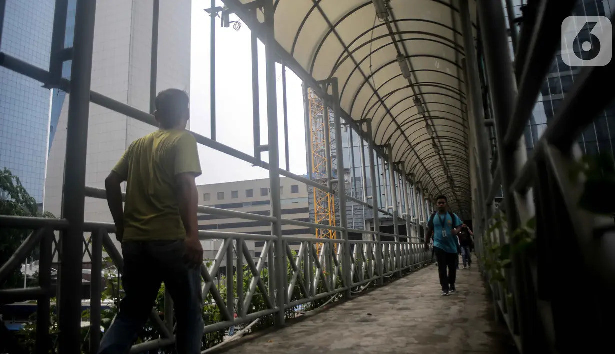Sejumlah warga melintas di jembatan penyeberangan orang (JPO) dekat Unika Atma Jaya, Jakarta, Rabu (13/11/2019). Kepala Dinas Bina Marga DKI Jakarta Hari Nugroho mengatakan atap JPO dekat Unika Atma Jaya dan Hotel Le Meridien di Jalan Jenderal Sudirman akan dicopot. (Liputan6.com/Faizal Fanani)