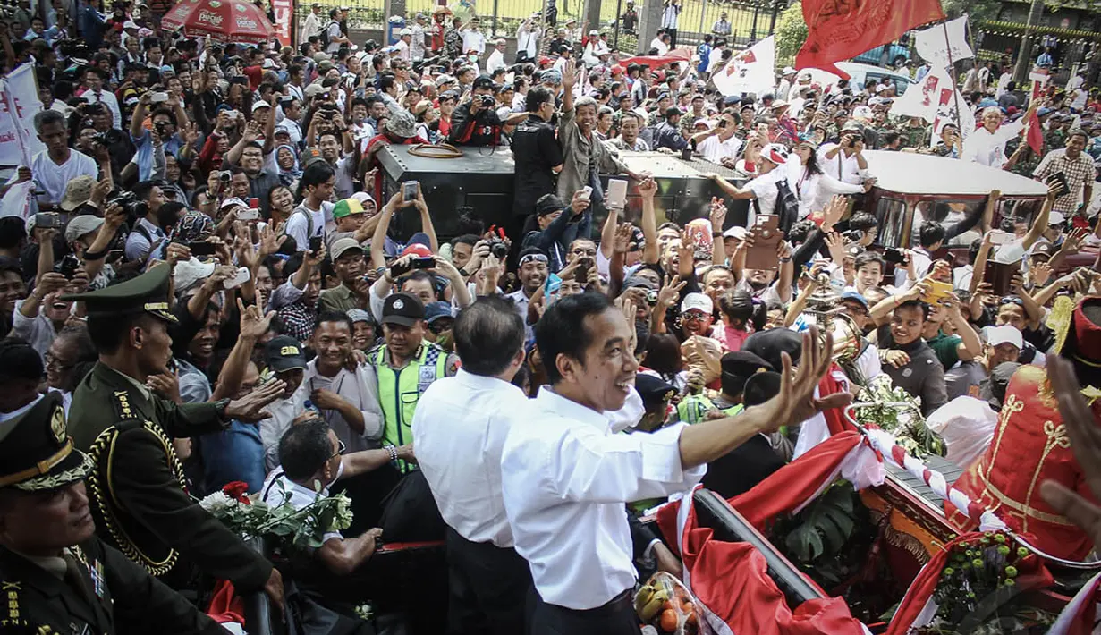 Jokowi-JK terus melempar senyum dan melambaikan tangan kepada ratusan warga yang menunggunya, Jakarta, (20/10/14). (Liputan6.com/Faizal Fanani) 