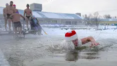 Seorang pria berpakaian seperti Ded Moroz (Santa Claus) berenang di air sedingin es selama hari yang membekukan di kota Omsk di Siberia, Rusia, Sabtu (26/12/2020). Suhu di Omsk turun hingga -32 derajat Celcius atau -25,6 derajat Fahrenheit. (AP Photo/Evgeniy Sofiychuk)