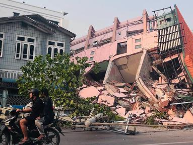 Orang-orang mengendarai sepeda motor melewati sebuah bangunan yang runtuh di Mandalay pada tanggal 28 Maret 2025, setelah gempa bumi di Myanmar tengah. (Foto: AFP)