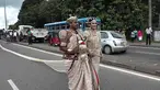 Sepasang pengantin Sri Lanka berjalan menyusuri jalan utama di pusat kota Kandy, 22 September 2017. Pasangan itu membuat kontroversi karena menggunakan sekitar 250 siswa untuk memegang saree atau gaun pengantin wanita India selama pernikahan. (STR/AFP)