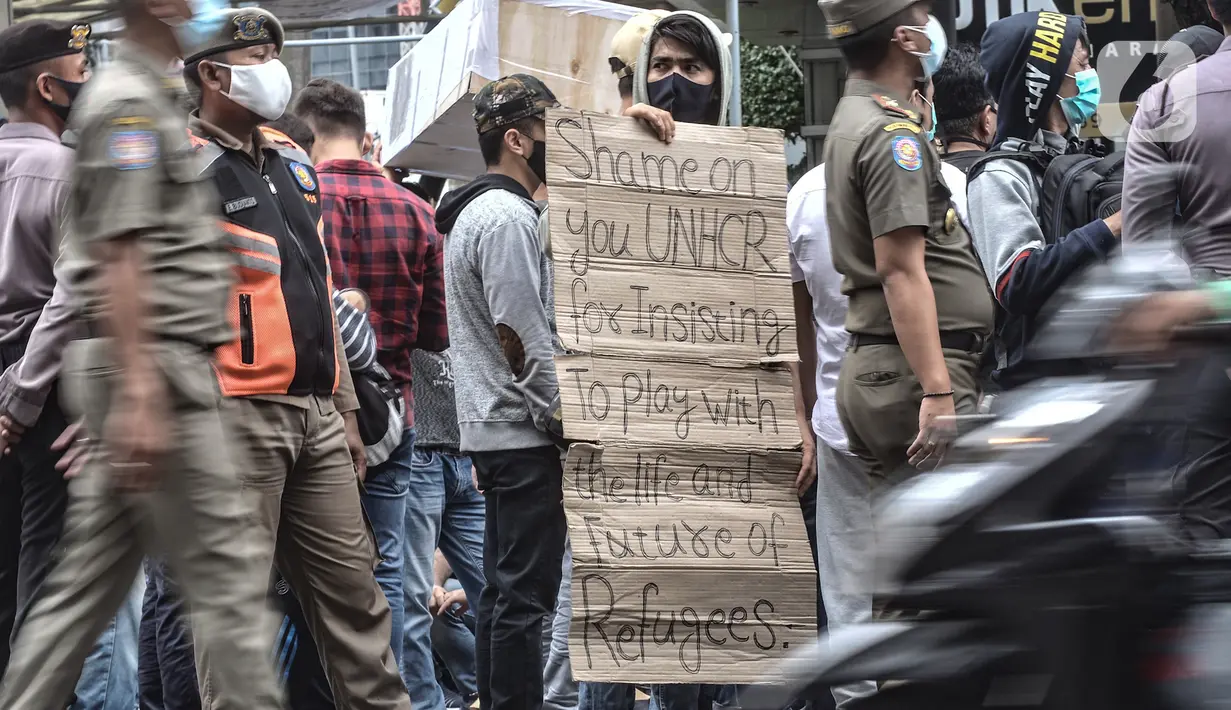Pencari suaka membawa poster saat unjuk rasa di depan kantor UNHCR, Jakarta, Senin (14/12/2020). Mereka meminta agar proses perpindahan ke negara tujuan dipercepat setelah adanya tiga orang pengungsi yang bunuh diri dalam dua minggu terakhir karena depresi. (merdeka.com/Iqbal Nugroho)