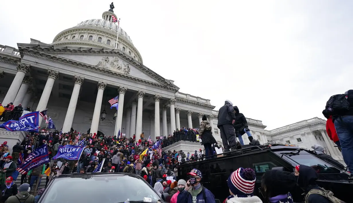 Ribuan massa pendukung Trump menyerbu ke dalam Gedung Kongres di Capitol Hill untuk menolak pengesahan hasil pemilihan presiden 2020 pada Rabu (6/1). Untuk membubarkan massa,, aparat menembakkan gas air mata hingga terlibat baku hantam. (AP Photo/Julio Cortez)