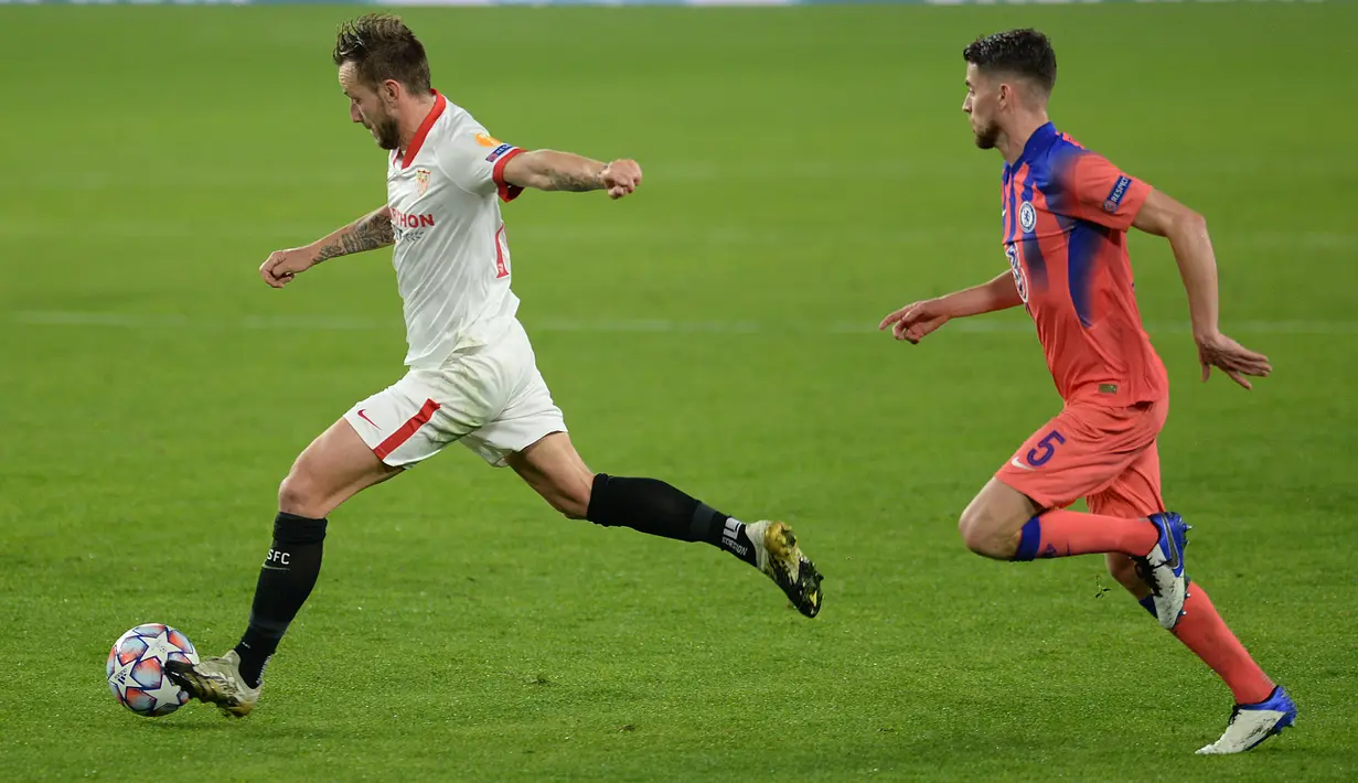 Gelandang Sevilla, Ivan Rakitic  berlari dengan bola melewati gelandang Chelsea, Jorginho pada matchday kelima Grup E Liga Champions di Estadio Ramon Sanchez Pizjuan, Sevilla, Kamis (3/12/2020) dinihari WIB. Olivier Giroud memborong empat gol saat Chelsea mencukur Sevilla 4-0. (CRISTINA QUICLER/AFP)
