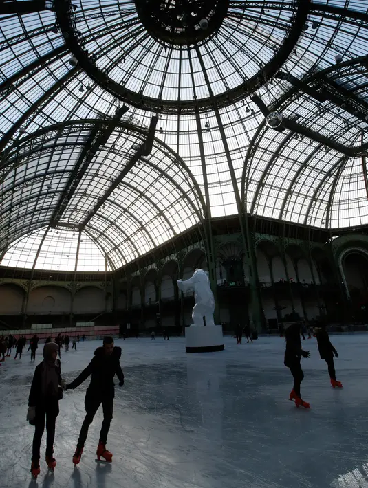 Orang-orang  berseluncur di arena ice skating di bawah kubah kaca mewah legendaris, Grand Palais, Paris, Senin (17/12). Arena ice skating musiman ini terbuka untuk umum selama liburan Natal. (AP Photo/Christophe Ena)