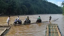 Sebuah rakit mengangkut motor dan warga menyeberangi Sungai Cisadane di Rumpin, Bogor, Selasa (13/3). Mereka terpaksa menaiki rakit akibat jembatan Gerendong yang merupakan akses jalan utama Ciseeng -Rumpin masih dalam perbaikan. (Merdeka.com/Arie Basuki)