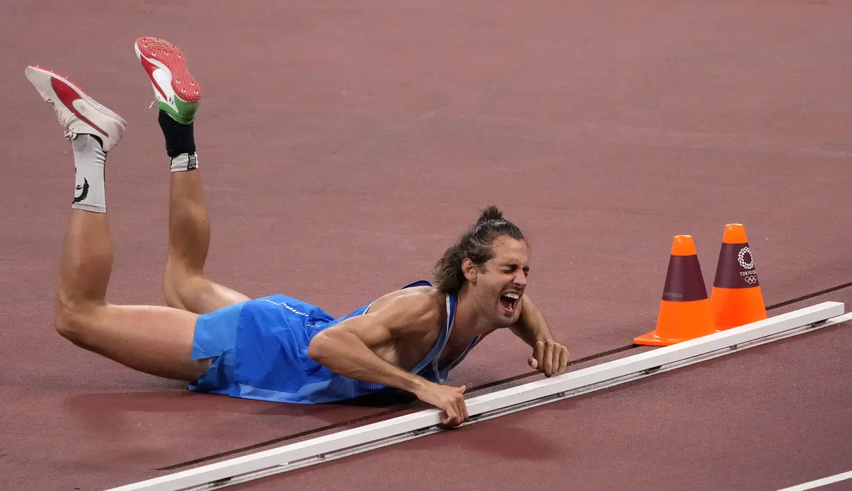 Gianmarco Tamberi dari Italia bereaksi setelah memenangkan emas bersama dengan Mutaz Barshim dari Qatar di final lompat tinggi putra Olimpiade Tokyo 2020 di Tokyo, Jepang, Minggu (1/8/2021). Panitia menyetujui Tamberi dan Mutaz Barshim berbagi emas Olimpiade. (AP Photo/Charlie Riedel)