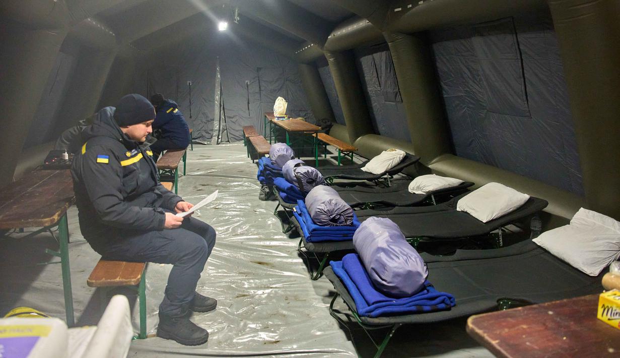 Sejak Sabtu 10 Januari 2026, sejumlah teknisi telah dikerahkan untuk menstabilkan sistem kelistrikan yang berada di ambang krisis, menyusul serangan besar dua hari sebelumnya. Tampak dalam foto, seorang petugas darurat menunggu orang-orang di salah satu tenda tempat mereka menghangatkan diri dan beristirahat setelah serangan udara rutin Rusia terhadap fasilitas energi negara itu di tengah musim dingin, Kyiv, Ukraina, Selasa 13 Januari 2026. (AP Photo/Efrem Lukatsky)