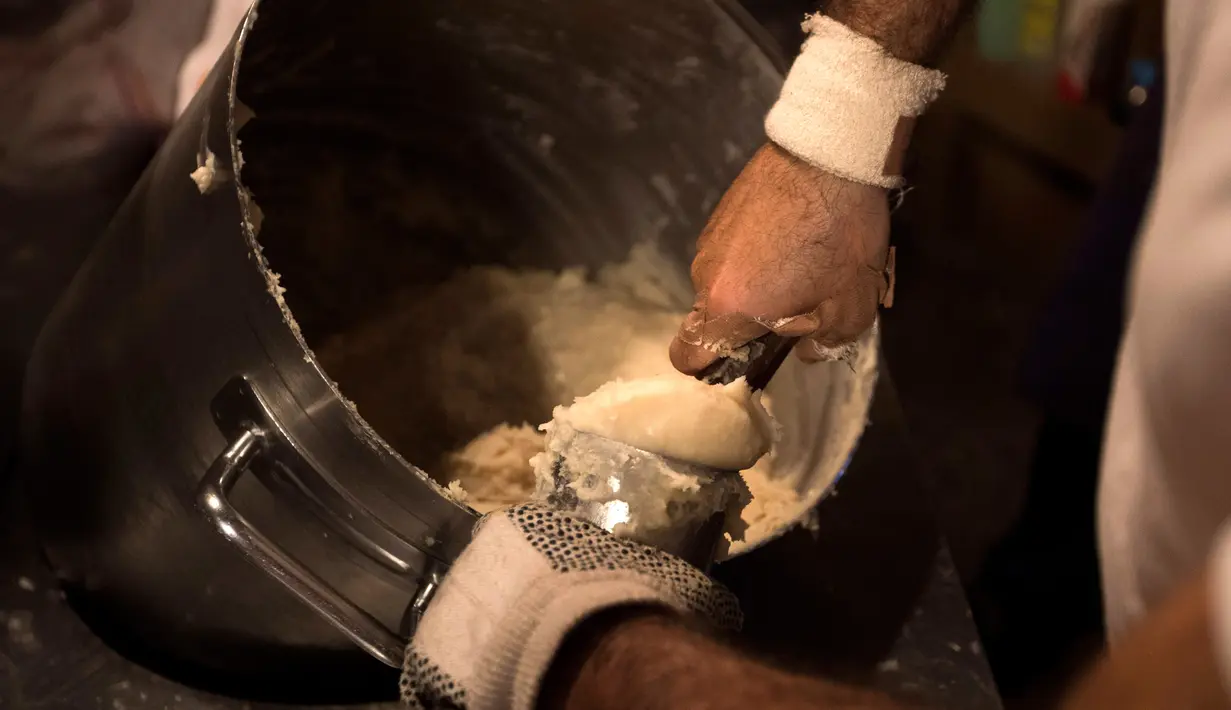 Karyawan mengaduk adonan donat khas Spanyol atau churros di restoran dessert tradisional La Manueta, Pamplona, Spanyol, Rabu (10/7/2019). Kue ini memiliki bahan utama tepung terigu dan dibentuk sedemikian rupa sehingga berbentuk memanjang. (JAIME REINA/AFP)