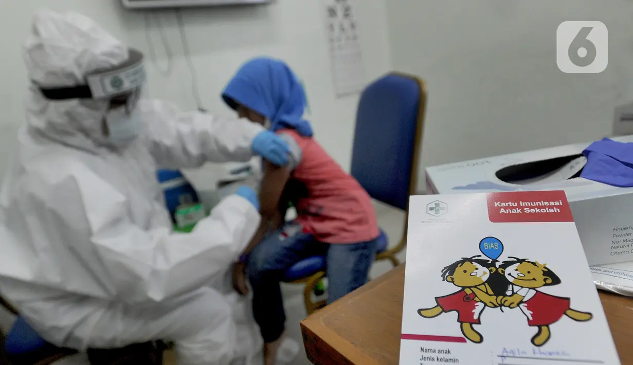 Dokter memberikan imunisasi campak kepada murid baru sekolah dasar negeri di Puskesmas Pondok Labu, Jakarta Selatan, Rabu (12/8/2020). Selain dalam rangka Bulan Imunisasi Anak Sekolah, kegiatan ini juga bagian dari pemeriksaan kesehatan murid baru sekolah dasar negeri. (merdeka.com/Arie Basuki)