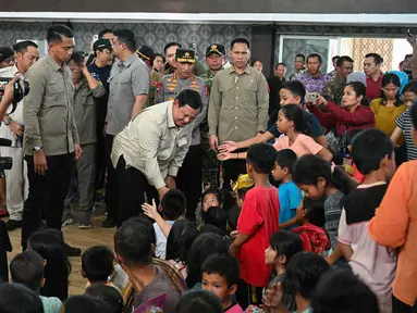 Presiden Republik Indonesia, Prabowo Subianto (tengah), bertemu dengan anak-anak korban banjir bandang di posko pengungsian Pandan, Tapanuli Tengah, Provinsi Sumatera Utara, pada 1 Desember 2025. Presiden Republik Indonesia, Prabowo Subianto mengunjungi meninjau langsung penanganan dampak banjir yang melanda Tapanuli Tengah, Provinsi Sumatera Utara, pada Senin 1 Desember 2025. (YT Hariono/AFP)