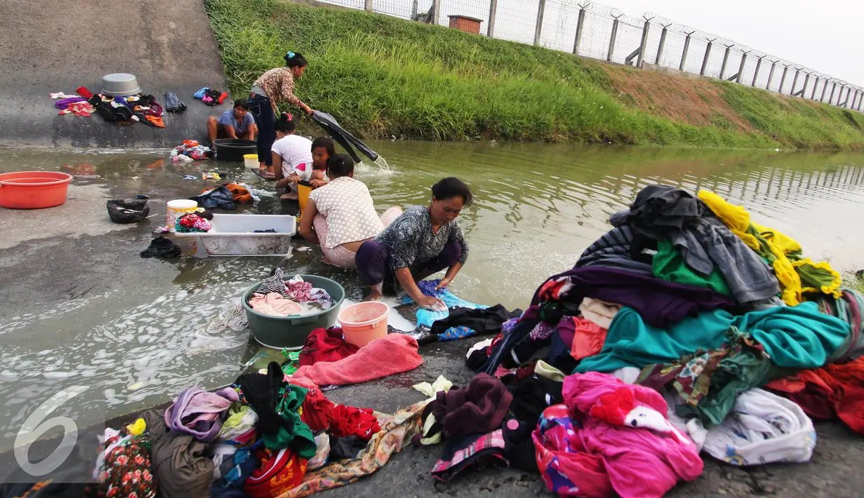Warga mencuci pakaian di sungai yang menjadi pembatas di area Bandara Soetta, Tangerang (28/9/2015). Akibat kemarau panjang membuat pasokan air menjadi kering sehinga warga yang bermukim nekat menerobos pagar untuk mencuci. (Liputan6.com/Angga Yuniar)