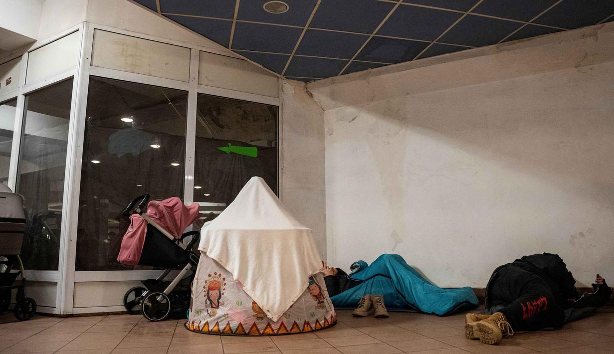 Otoritas setempat mendesak warga untuk tetap berada di dalam tempat perlindungan sampai sirene serangan udara berhenti berbunyi. Tampak dalam foto, warga berlindung di stasiun metro selama serangan pesawat tak berawak dan rudal Rusia di Kyiv, Ukraina, pada 9 Januari 2026 pagi hari waktu setempat, di tengah invasi Rusia ke Ukraina. (Serhii Okunev/AFP)