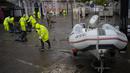 Pekerja kota membersihkan jalan yang terendam banjir semalam di Alges, tepat di luar Lisbon, Selasa (13/12/2022). Badai Atlantik menghantam semenanjung Iberia, meninggalkan jejak kehancuran pada Selasa, terutama di Ibu kota Portugal,  Lisbon, sebelum pindah ke timur ke Spanyol.  (AP Photo/Armando Franca)