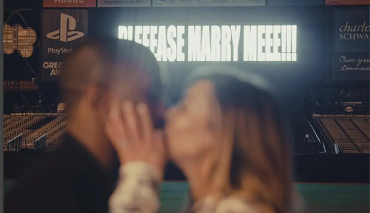 Tampak di layar score sebuah tulisan bertuliskan 'Please Marry Meee!!! (Tolong menikah denganku!)' sementara Kim dan Kanye berciuman membelakangi tulisan itu. (Via Instagram/@kimkardashian)