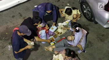 Pemudik makan bersama sambil menanti waktu masuk kapal di Dermaga II Pelabuhan Penyebrangan Merak, Banten, Senin (3/6/2019). Sambil menanti waktu bongkar muat kapal penyebrangan, pemudik memanfaatkan waktu untuk makan bersama. (Liputan6.com/Helmi Fithriansyah)