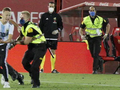 Petugas keamanan menangkap seorang penyusup yang masuk ke lapangan saat pertandingan La Liga antara Mallorca dengan FC Barcelona di Son Moix Stadium, Palma de Mallorca, Spanyol, Sabtu (13/6/2020). Dalam pertandingan tersebut Barcelona mengalahkan Mallorca dengan skor 4-0. (AP Photo/Francisco Ubilla)