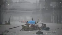 Tim penyelamat mendayung perahu mereka di sepanjang jalan yang banjir di ibu kota Filipina, Manila. [Ted Aljibe/AFP]