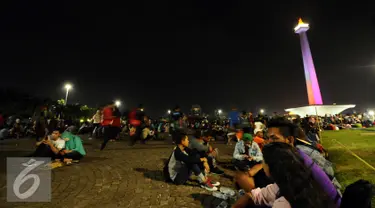 Pengunjung duduk duduk di halaman Monumen Nasional, Jakarta, Sabtu (31/12). Dengan alasan keamanan, Pemprov DKI Jakarta membatalkan panggung hiburan malam pergantian tahun di kawasan Monumen Nasional. (Liputan6.com/Helmi Fithriansyah)