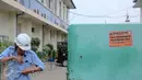 Pekerja berdiri dekat plang yang dipasang  di PT DKB Dok Perkapalan Galangan I, Tanjung Priok, Jakarta, Senin (23/11). Langkah ini sebagai peringatan bagi para wajib pajak (WP) kelas menengah ke atas mencapai ratusan miliar. (Liputan6.com/Faizal Fanani)