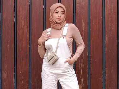 Gaya OOTD berhijab Awkarin bisa jadi inspirasi dengan memadukan busana berwarna pink soft dengan jumpsuit putih ini. Hijab simpel berwarna senada menambah gaya casual (Liputan6.com/IG/@awkarin)