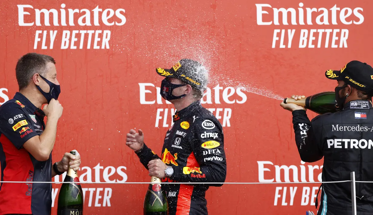 Pembalap Mercedes Lewis Hamilton (kanan) menyemprotkan sampanye ke pembalap Red Bull Max Verstappen yang memenangkan 70th Anniversary Formula 1 Grand Prix di Sirkuit Silverstone, Silverstone, Inggris, Minggu (9/8/2020). Max Verstappen tercepat di F1 GP Silverstone 2020. (Andrew Boyers, Pool via AP)