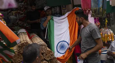 Seorang penjaga toko mengangkat bendera nasional untuk dijual menjelang Hari Kemerdekaan India di Mumbai, India, Selasa, 2 Agustus 2022. Perdana Menteri India Narendra Modi telah mengimbau warga untuk mengibarkan atau memajang bendera nasional di Hari Kemerdekaan pada 15 Agustus. (AP Photo/Rafiq Maqbool)