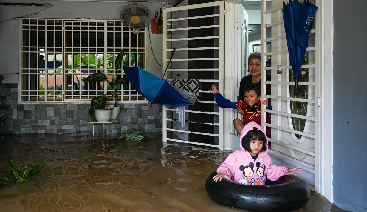 Seorang perempuan dan anak-anaknya bersiap untuk mengungsi dari rumah mereka di daerah banjir di Yong Peng, negara bagian Johor Malaysia, Sabtu (4/3/2023). Banjir di Malaysia biasa terjadi selama musim hujan tahunan antara Oktober dan Maret, tetapi hujan deras minggu ini membuat banyak penduduk Johor berebut mencari tempat berlindung. (Photo by Mohd RASFAN / AFP)