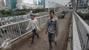 Dua pejalan kaki melintas di atas JPO di kawasan Grogol, Jakarta, Rabu (4/5). JPO yang seharusnya diperuntukkan bagi pejalan kaki itu kini sering dimanfaatkan pengendara motor untuk jalan pintas. (Liputan6.com/Gempur M Surya)