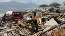Polisi menggendong anjing K9 saat mencari korban di antara puing bangunan usai gempa dan tsunami menerjang Palu, Sulawesi Tengah, Rabu (3/10). Anjing K9 dikerahkan untuk mengendus keberadaan korban yang tertimbun reruntuhan. (AP Photo/Tatan Syuflana)