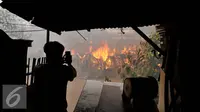 Seorang warga mengabadikan gambar saat terjadinya kebakaran yang melanda rumah hunian semi permanen di bantaran sungai anak kali ciliwung, Kawasan Kampung Berland, Jakarta, Rabu (2/9/2015). (Liputan6.com/Johan Tallo)