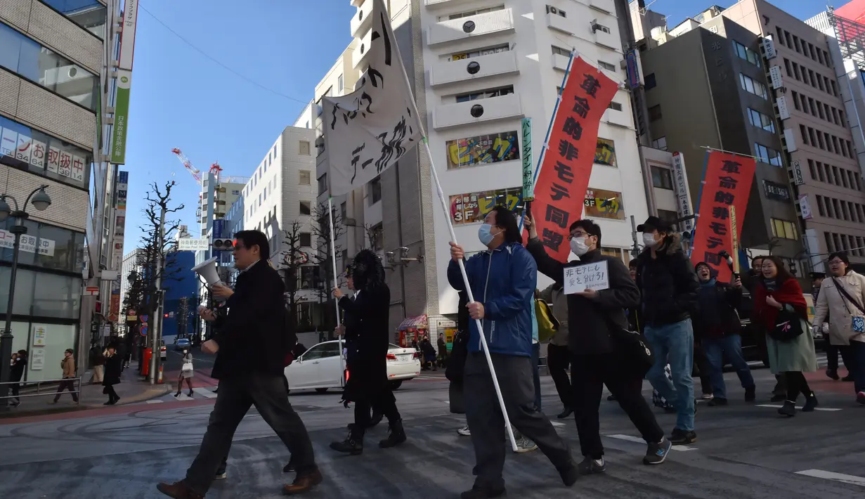 Sekelompok pria Jepang membawa spanduk sambil meneriakkan berbagai yel saat menggelar demonstrasi anti-Valentine di Tokyo, Minggu (12/1). Para pria tersebut mengklaim, pasangan yang merayakan hari Valentine melukai hati mereka. (KAZUHIRO NOGI/AFP)