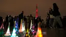 Wisatawan berjalan melewati replika Menara Eiffel yang dijual saat pertunjukan instalasi cahaya di Paris, Perancis, Kamis (13/9). Pertunjukan ini bagian dari kunjungan Putra Mahkota Jepang, Naruhito. (AP Photo/Christophe Ena)