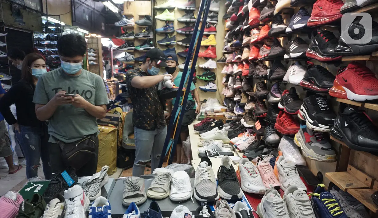 Pedagang sepatu melayani pembeli di Taman Puring, Jakarta,Rabu (21/10/2020). Menurut pedagang penjualan sepatu di lokasi tersebut menurun hingga sebesar 60% akibat sepinya pengunjung di masa pandemi. (Liputan6.com/Angga Yuniar)