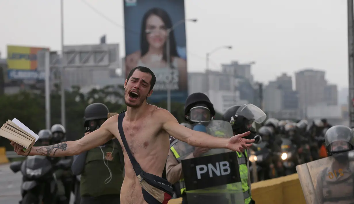 Seorang demonstran berteriak saat unjuk rasa di Caracas, Venezuela (20/4). Di tengah bentrokan seorang demonstran bugil dan maju menghadang petugas. (AP Photo/Fernando Llano)