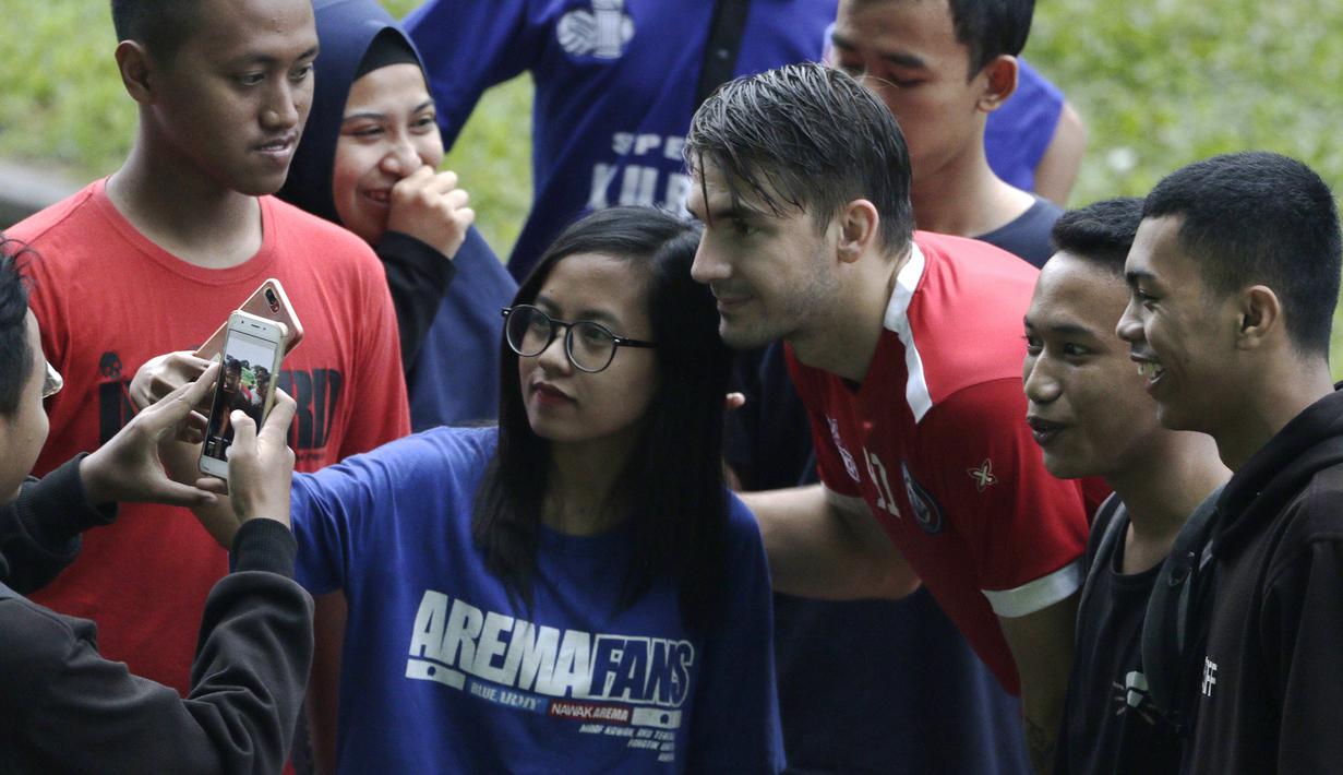 Pemain Arema FC, Pavel Smolyachenko, foto bersama fans usai sesi latihan di Stadion Gajayana, Malang, Kamis (11/4). Setelah sesi latihan, pemain Arema FC melayani permintaan fans untuk foto bersama. (Bola.com/Yoppy Renato)