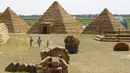 Pengunjung berjalan di sekitar replika Piramida Giza yang terbuat dari jerami di permukiman Krasnoye, Rusia, Rabu (19/7). Piramida unik itu salah satu bangunan yang menghiasi taman jerami di wilayah pertanian Ponomaryovo. (REUTERS/Eduard Korniyenkov)