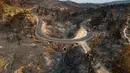 Pemandangan udara ini menunjukkan sebuah jalan yang membentang di sepanjang lahan yang terbakar akibat kebakaran hutan di dekat desa Jonquieres, di departemen Aude, Prancis Selatan, pada 18 Agustus 2025. (Lionel BONAVENTURE/AFP)